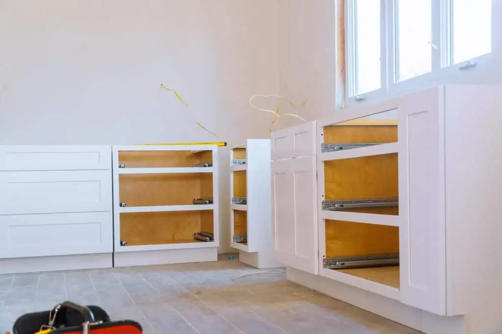 New white kitchen cabinets being installed in a home renovation.